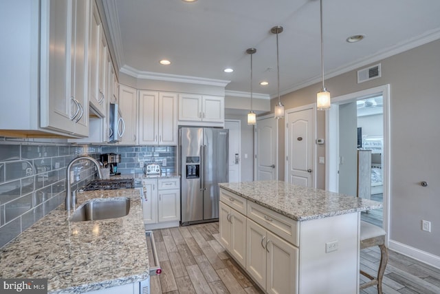 kitchen featuring pendant lighting, sink, appliances with stainless steel finishes, white cabinets, and a kitchen island