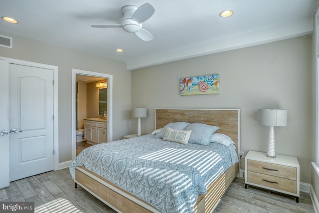 bedroom with ceiling fan, ensuite bathroom, and light wood-type flooring