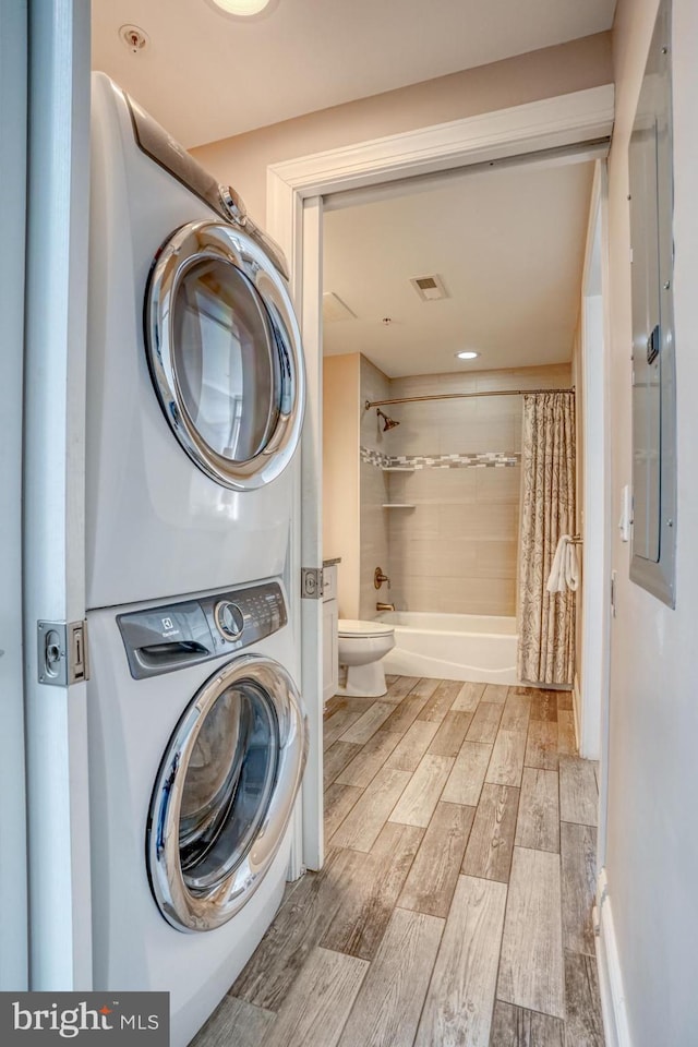 laundry area featuring stacked washer / drying machine and electric panel