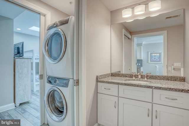 washroom featuring stacked washer and dryer, sink, and light wood-type flooring