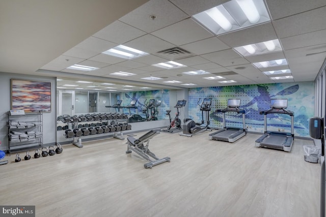 exercise room with a paneled ceiling and wood-type flooring