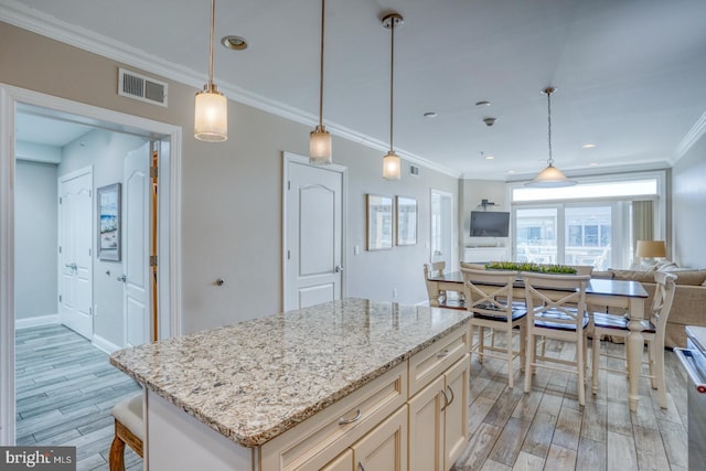 kitchen featuring pendant lighting, crown molding, light stone countertops, and a center island