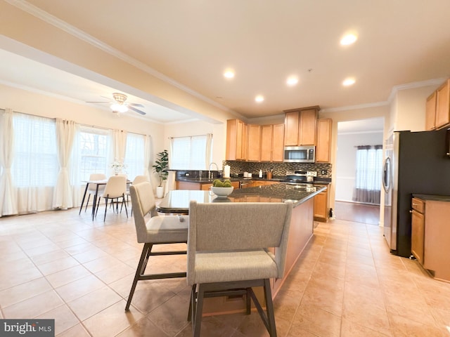 kitchen featuring light tile patterned floors, ornamental molding, appliances with stainless steel finishes, ceiling fan, and backsplash