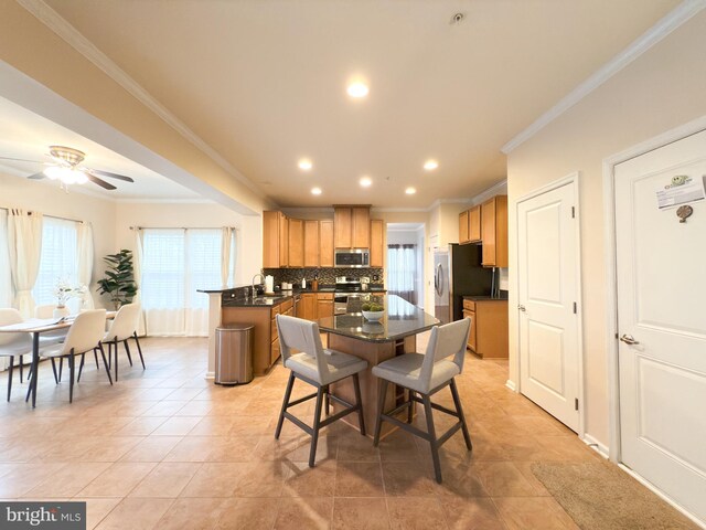 kitchen featuring stainless steel appliances, ornamental molding, a healthy amount of sunlight, and backsplash