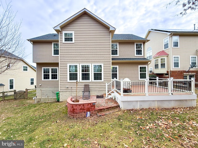 rear view of property with a wooden deck and a lawn