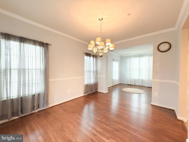 empty room featuring crown molding, a notable chandelier, and hardwood / wood-style flooring