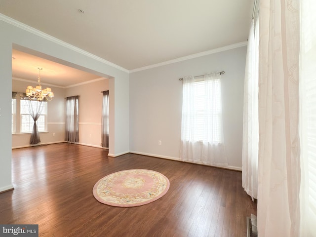 empty room featuring an inviting chandelier, dark wood-type flooring, and ornamental molding