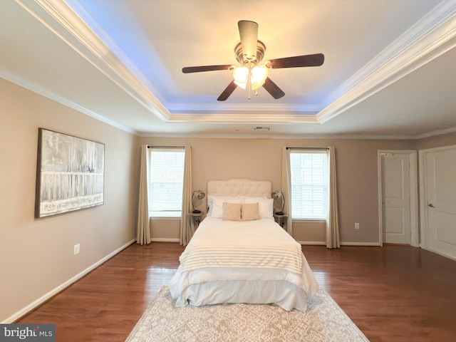 bedroom featuring multiple windows, dark hardwood / wood-style flooring, and a raised ceiling