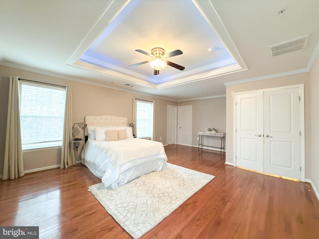 bedroom featuring hardwood / wood-style flooring, ornamental molding, and a tray ceiling