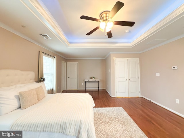 bedroom with crown molding, a tray ceiling, ceiling fan, and hardwood / wood-style flooring