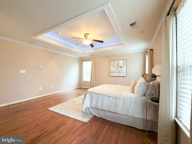 bedroom with ceiling fan, ornamental molding, a tray ceiling, and hardwood / wood-style floors