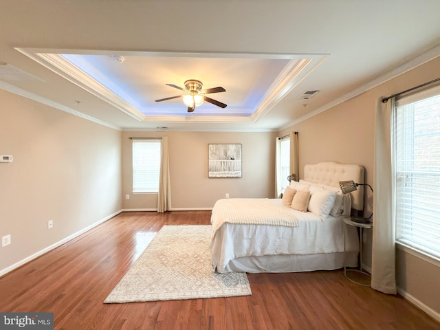 bedroom featuring hardwood / wood-style flooring, ornamental molding, a raised ceiling, and ceiling fan