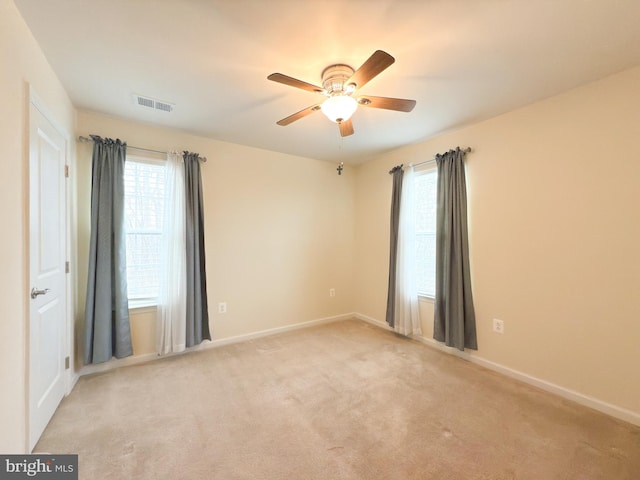 unfurnished room featuring a wealth of natural light, light colored carpet, and ceiling fan