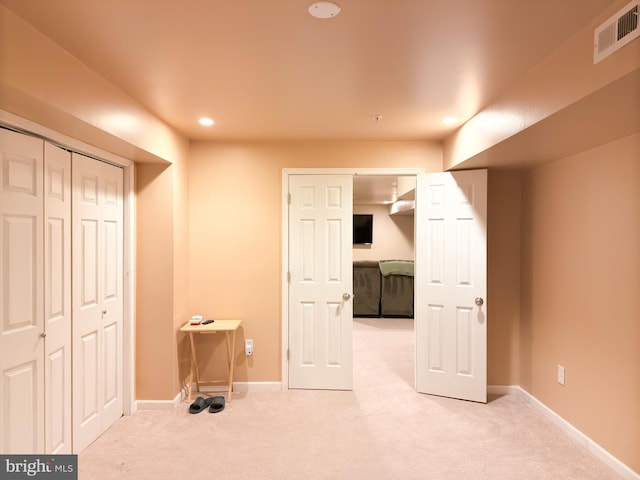 unfurnished bedroom with light colored carpet and a closet