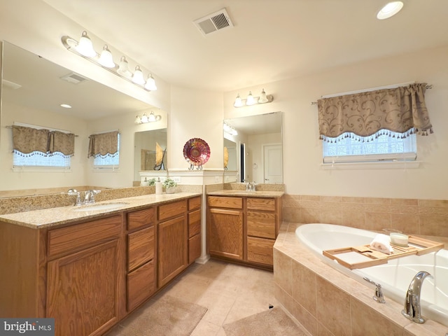 bathroom featuring vanity, a relaxing tiled tub, and tile patterned floors