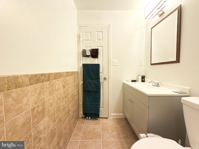 bathroom with tile walls, vanity, tile patterned flooring, and toilet