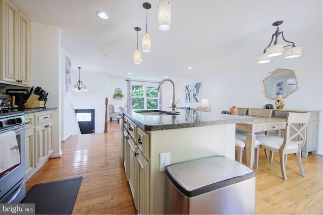 6406 Holyoke Dr, Annandale, VA 22003 - kitchen with a sink, light wood finished floors, a kitchen island with sink, cream cabinetry, and stainless steel electric stove