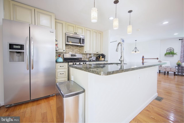 6406 Holyoke Dr, Annandale, VA 22003 - kitchen featuring appliances with stainless steel finishes, a sink, light wood-style flooring, decorative backsplash, and cream cabinetry
