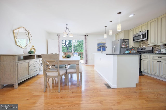 6406 Holyoke Dr, Annandale, VA 22003 - kitchen with cream cabinets, dark countertops, appliances with stainless steel finishes, light wood-style floors, and decorative backsplash