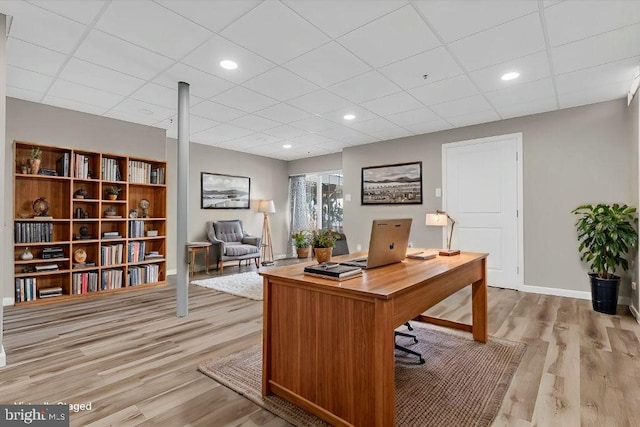 office space featuring a paneled ceiling and light hardwood / wood-style floors