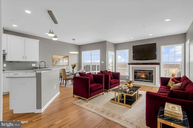 living room featuring sink, a high end fireplace, and light wood-type flooring