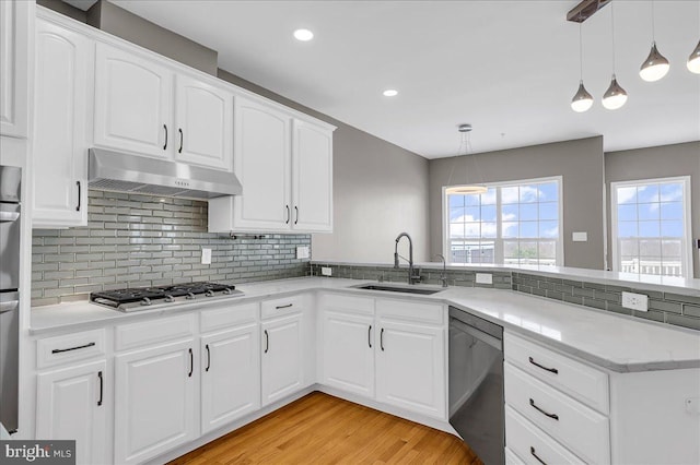 kitchen with white cabinetry, sink, dishwashing machine, and decorative light fixtures