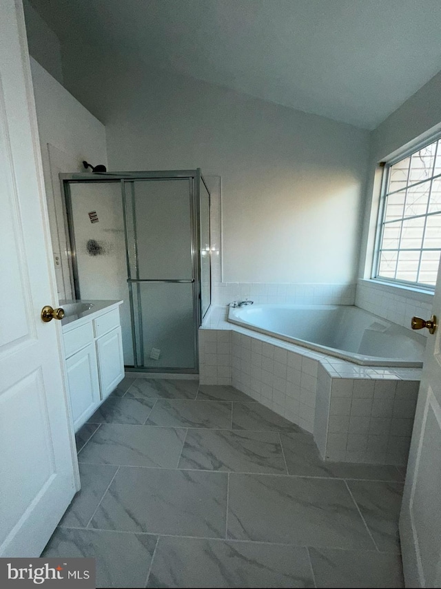 bathroom featuring independent shower and bath, vanity, and vaulted ceiling