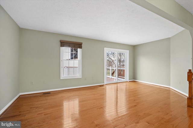 interior space with baseboards, a textured ceiling, and hardwood / wood-style floors