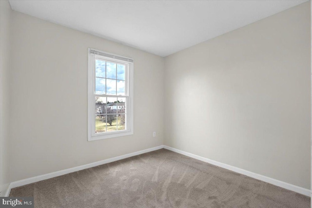 unfurnished room featuring carpet and baseboards