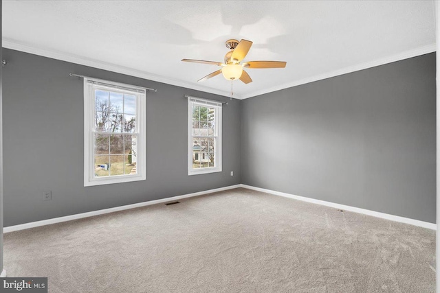 carpeted empty room featuring baseboards, visible vents, ornamental molding, and ceiling fan