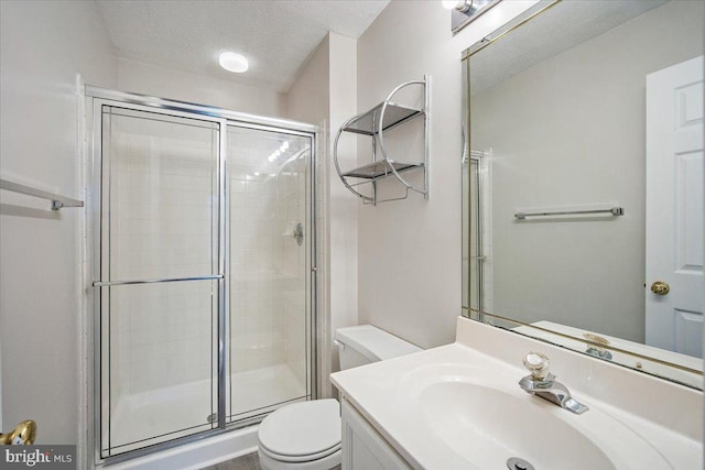 full bath with a stall shower, a textured ceiling, toilet, and vanity