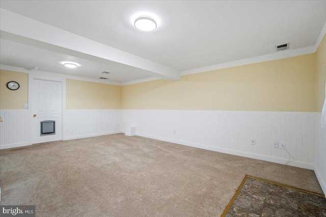 carpeted empty room featuring wainscoting and visible vents