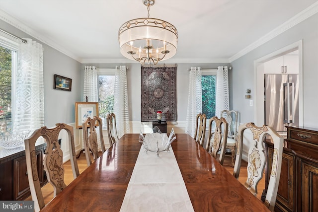 dining area featuring ornamental molding, a wealth of natural light, and an inviting chandelier