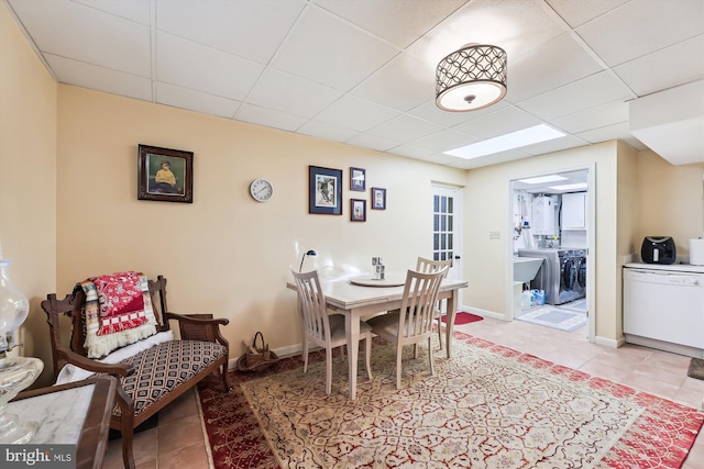 tiled dining room featuring a drop ceiling and washing machine and dryer