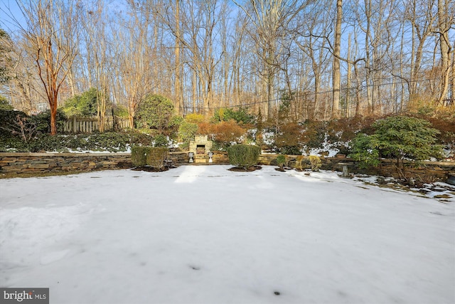 snowy yard with an outdoor stone fireplace