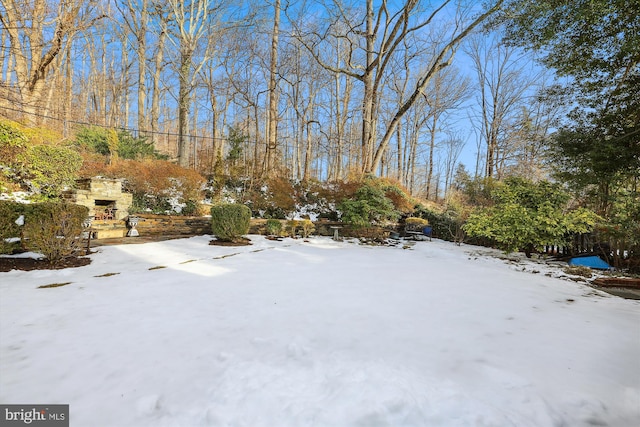 yard layered in snow with an outdoor stone fireplace