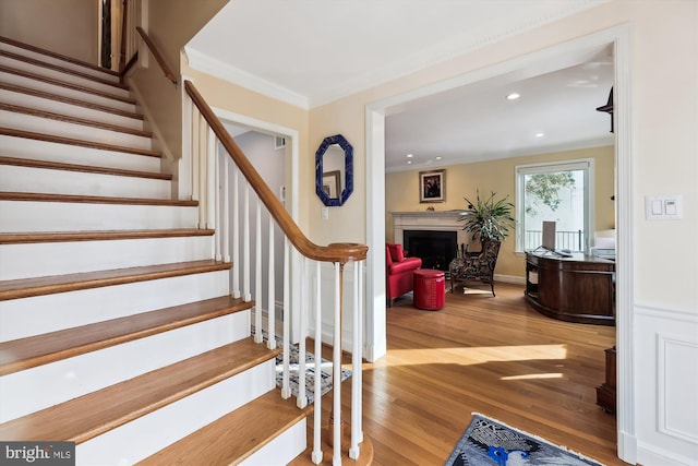 staircase with hardwood / wood-style floors and ornamental molding