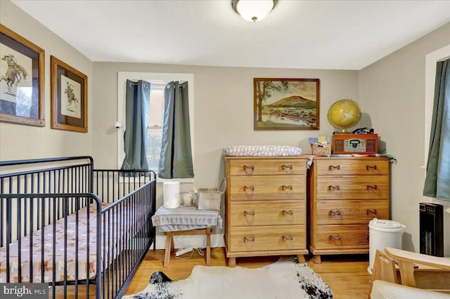 bedroom featuring a nursery area and light wood-type flooring