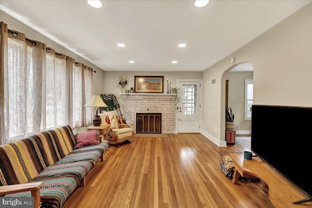 living room with a brick fireplace and light hardwood / wood-style floors