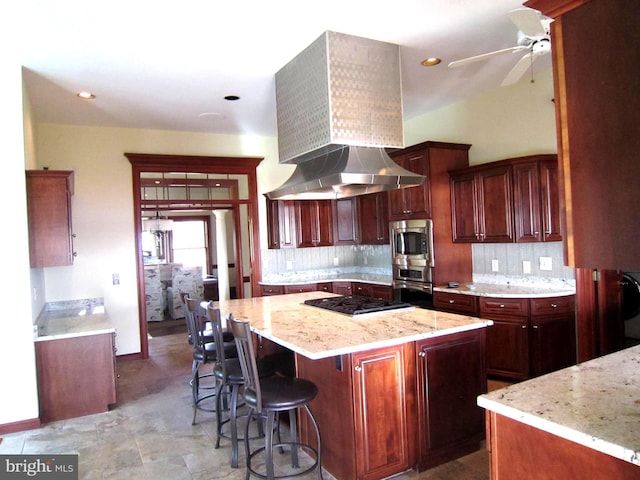 kitchen featuring stainless steel appliances, a center island, light stone counters, tasteful backsplash, and exhaust hood