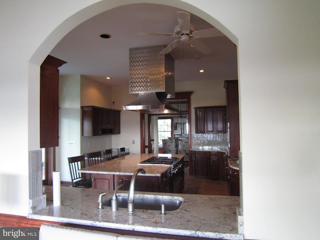 kitchen with light stone counters, kitchen peninsula, sink, and decorative backsplash