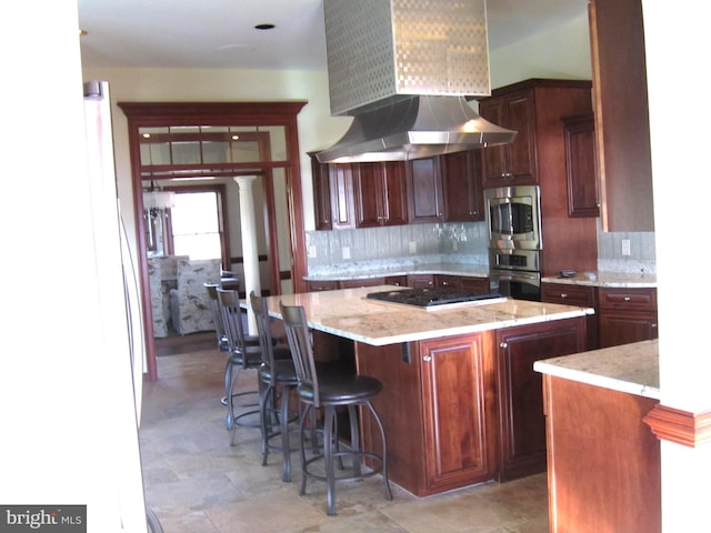 kitchen featuring light stone counters, black gas stovetop, a kitchen island, and backsplash