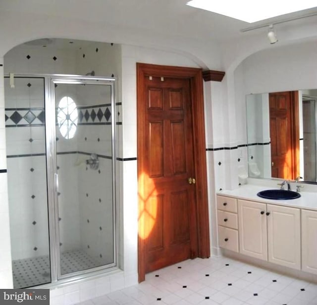 bathroom featuring a shower with door and vanity