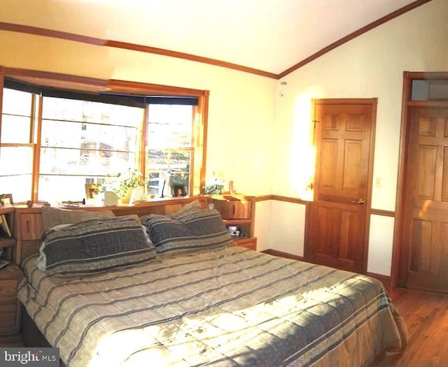 bedroom with hardwood / wood-style flooring, ornamental molding, and lofted ceiling