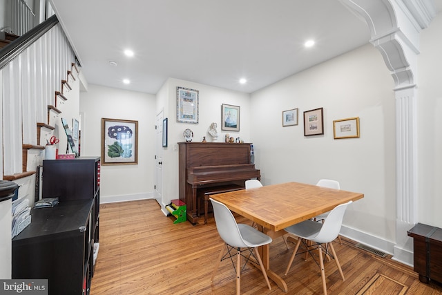 dining space with decorative columns and light wood-type flooring