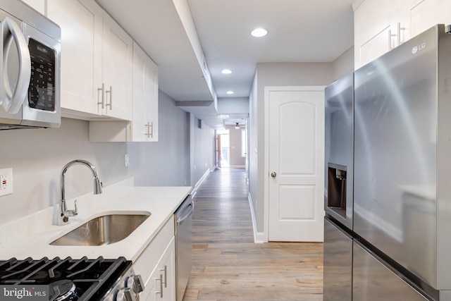 kitchen featuring sink, ceiling fan, stainless steel appliances, white cabinets, and light wood-type flooring