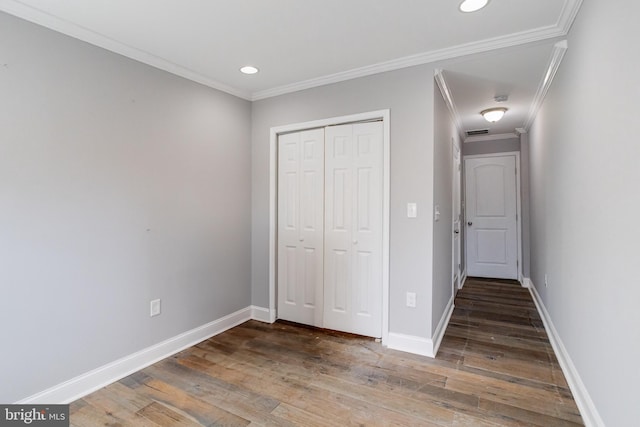 unfurnished bedroom with crown molding, dark hardwood / wood-style floors, and a closet