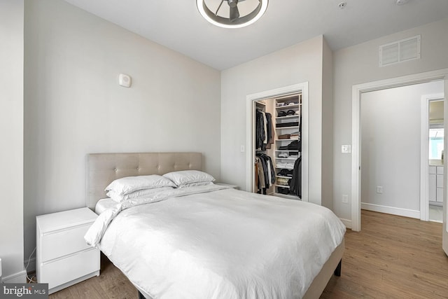 bedroom with a closet, a walk in closet, and light hardwood / wood-style flooring