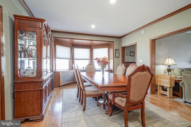 dining area featuring ornamental molding, radiator, and light wood-type flooring