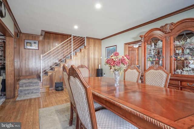 dining room with hardwood / wood-style flooring, crown molding, and wooden walls